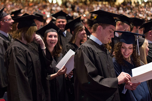 Students smile as they review the Commencement Ceremony program in the i-Center.