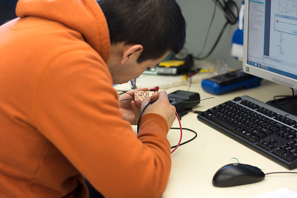 An Electrical Engineer student solders on an electrical component.