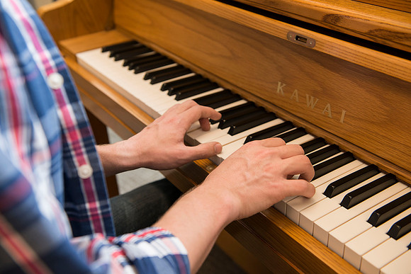 Students practice playing the piano for the new housing promo pictures.