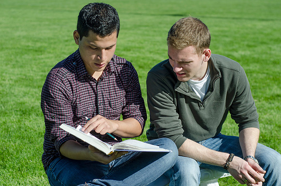 Two friends study outside in the sun.