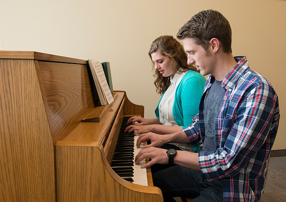 Students practice playing the piano for the new housing promo pictures.