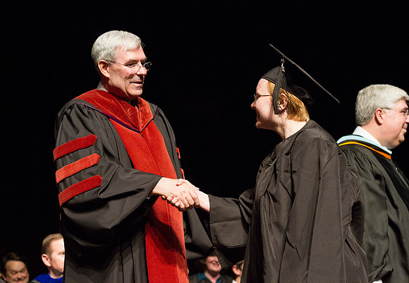 Edwin A. Sexton shakes hands with a graduate from the College of Business and Communication in the Hart Auditorium during Convocation.