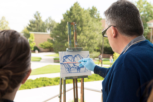 Brother Bodily gives a painting demonstration during his Oil Painting class outside the Spori Building.